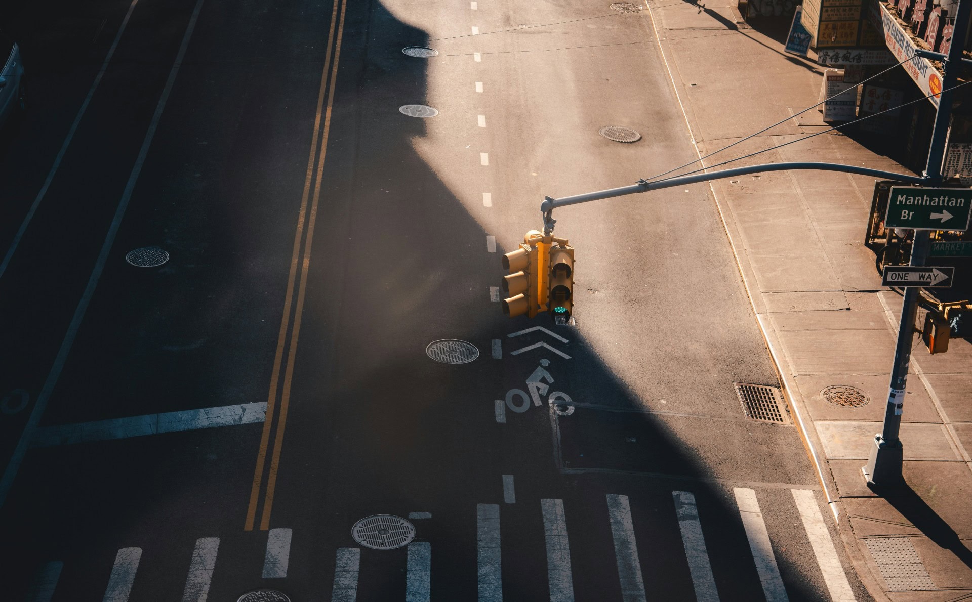An empty city street with crosswalks, traffic signals, and street signs during late afternoon lighti.