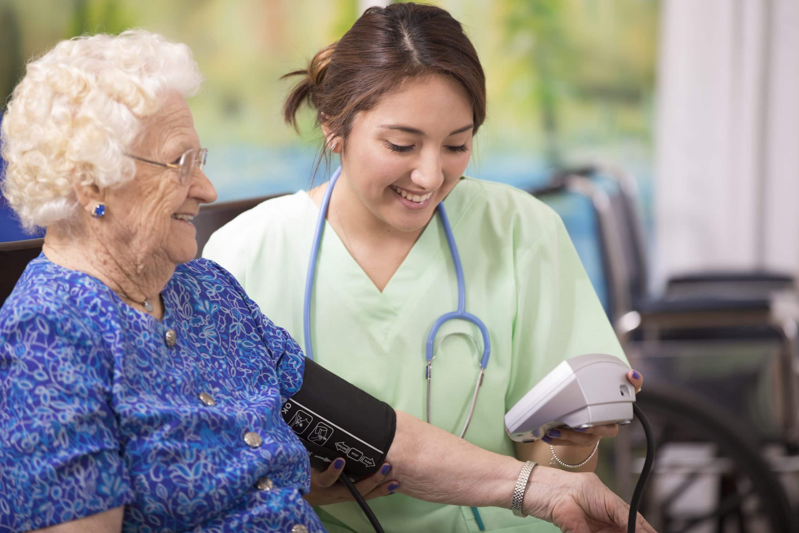 Caring nurse checking blood pressure of elderly woman in senior living facility.