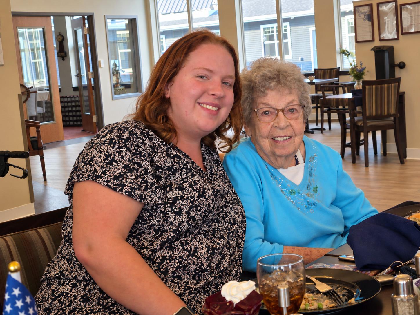 Happy resident and caregiver enjoying meal at Bella Largo senior living.