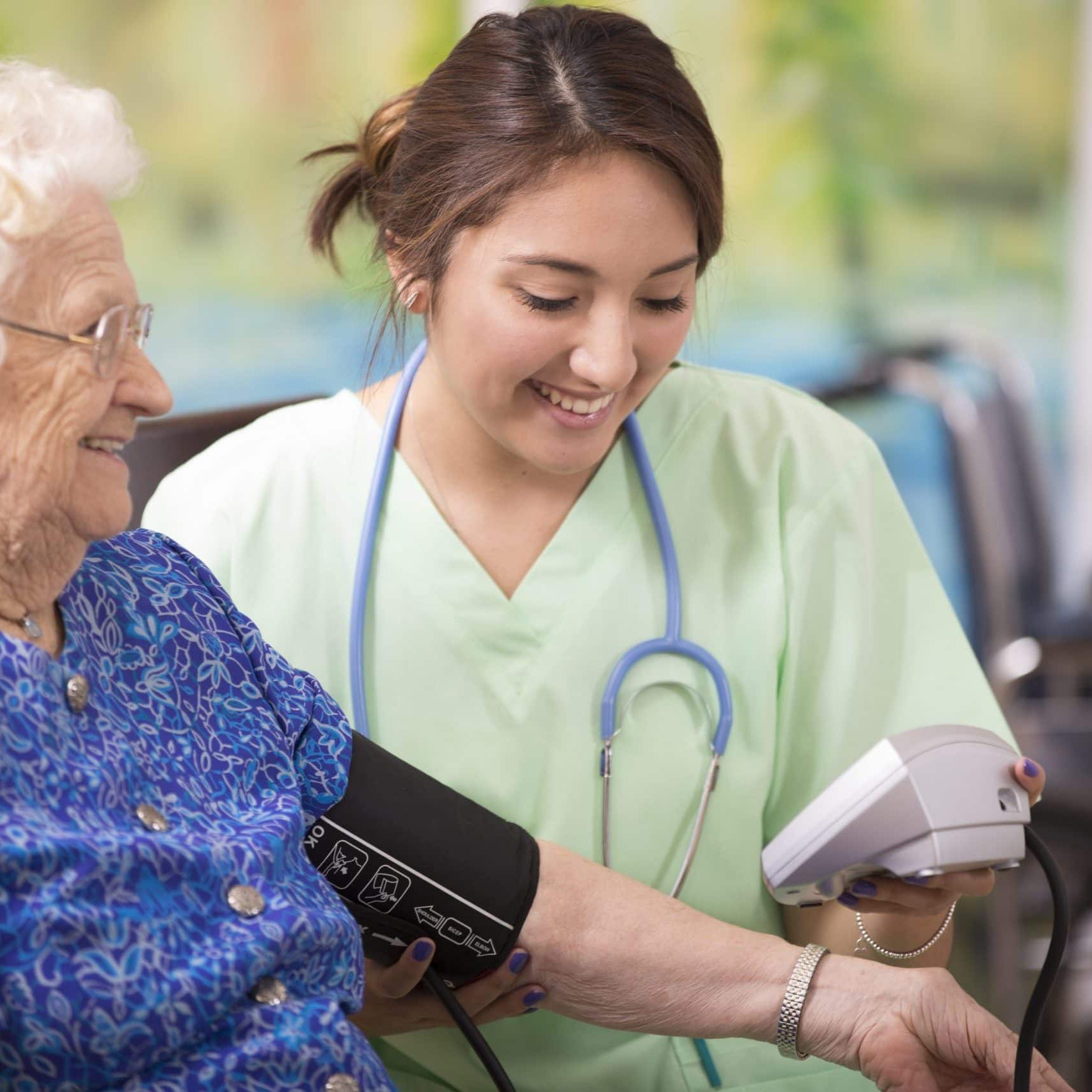 Caring nurse checking blood pressure of elderly woman in senior living facility.