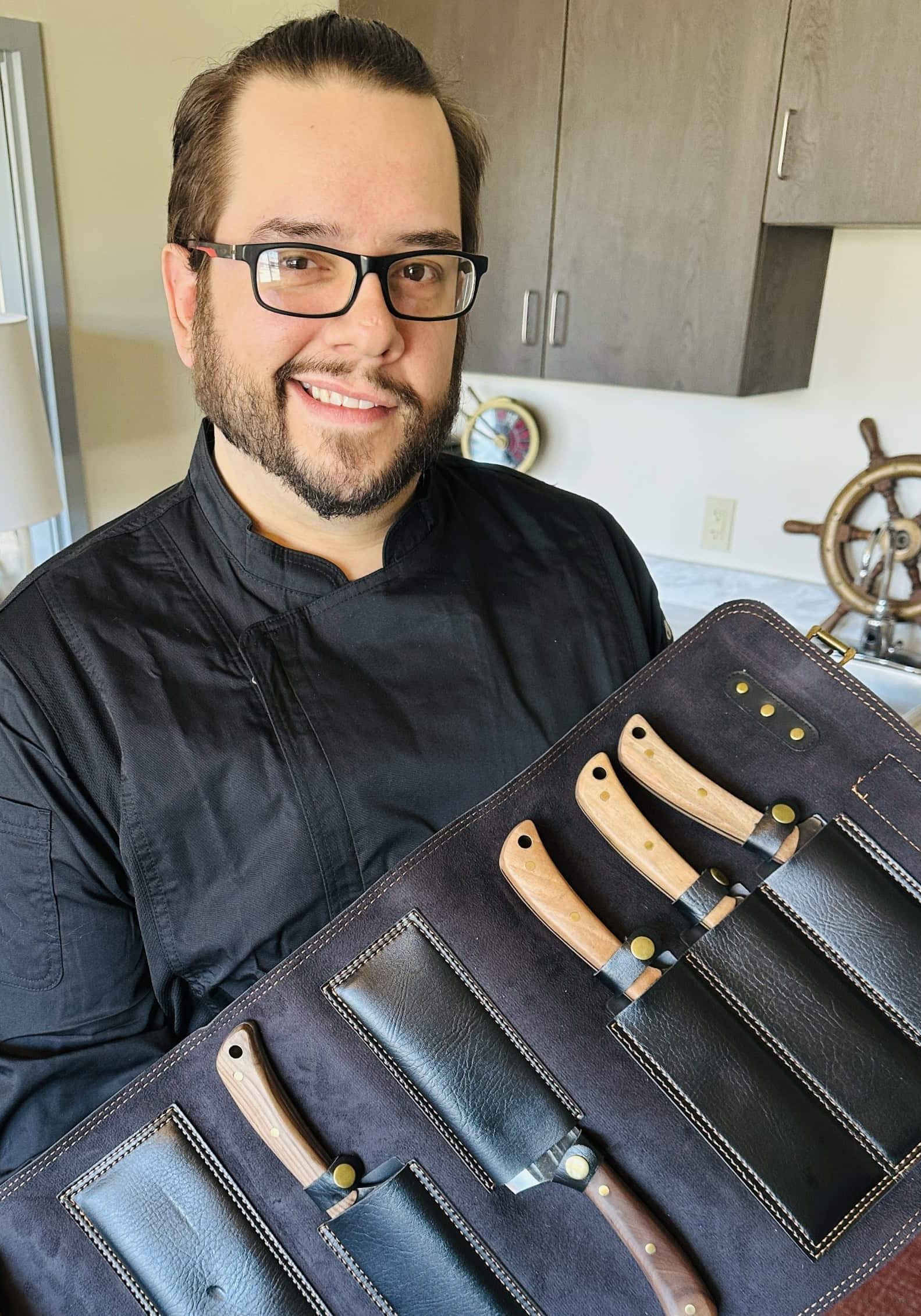 Chef holding a knife set display with various knives in a senior living kitchen.