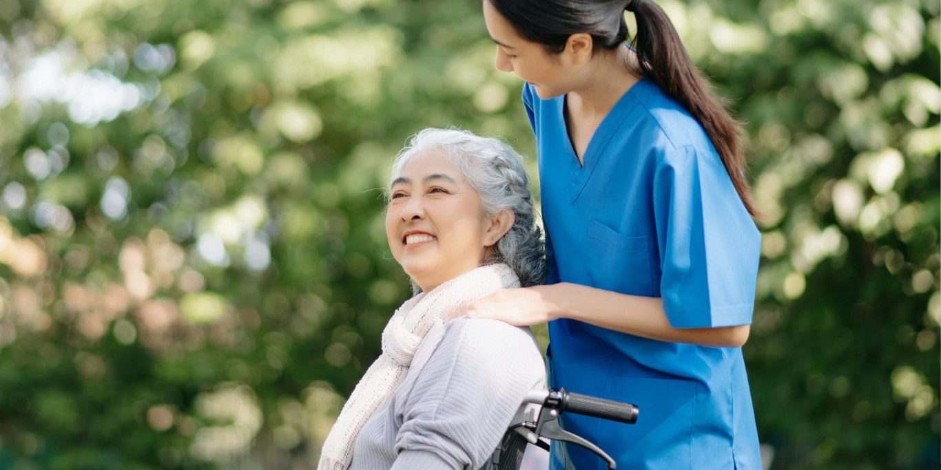 Caregiver assisting an elderly woman outdoors at Bella Largo Senior Living.
