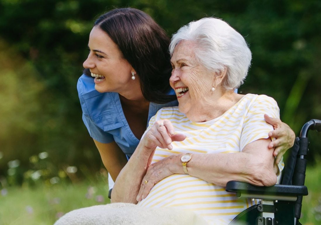 Happy senior woman in wheelchair enjoying outdoor activities with caregiver.