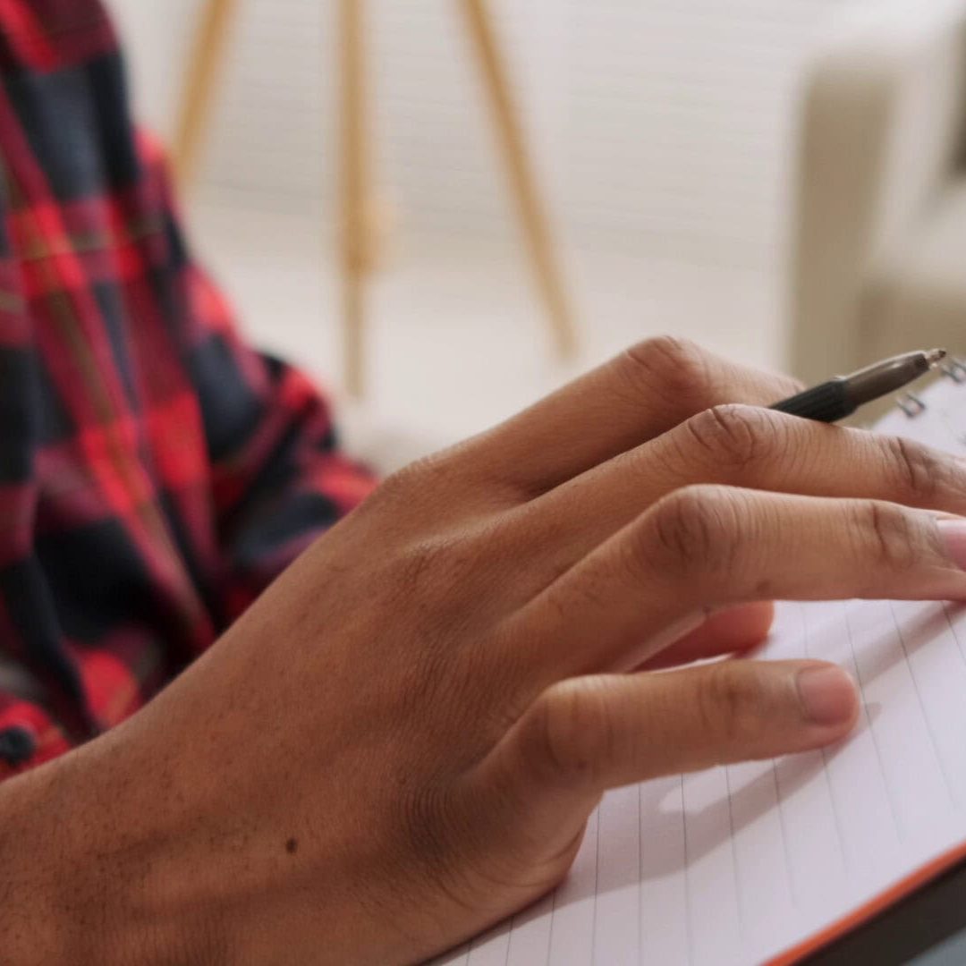 Person writing in a notebook, evaluating senior care facilities.