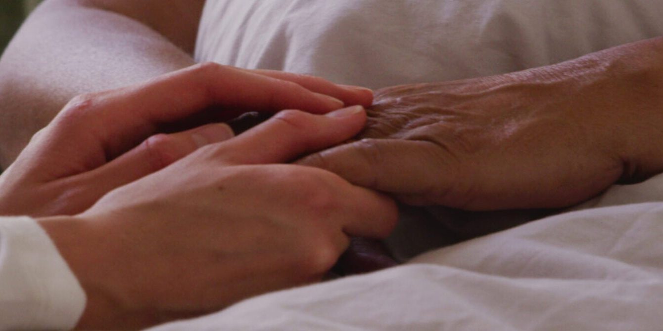 Elderly person receiving compassionate care from caregiver in a senior living setting.