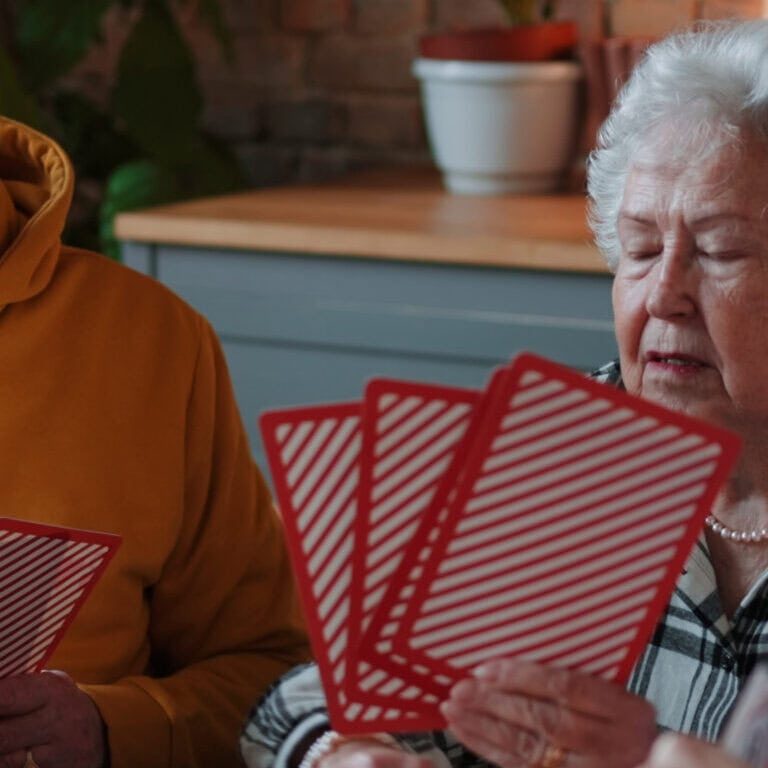 Seniors engaging in a card game in memory care community.